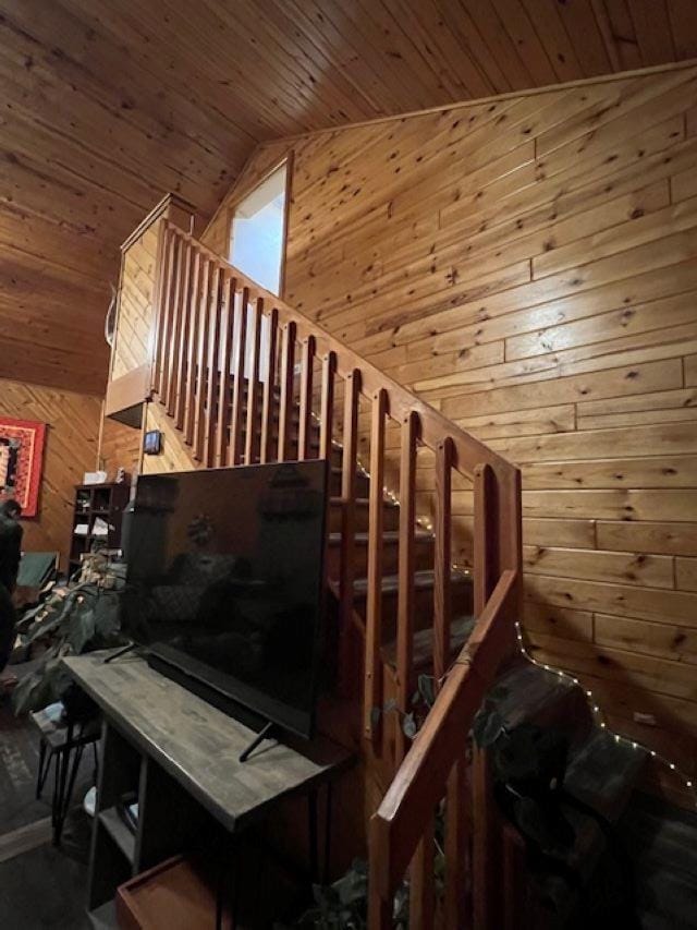 stairway with lofted ceiling, wooden ceiling, and wooden walls