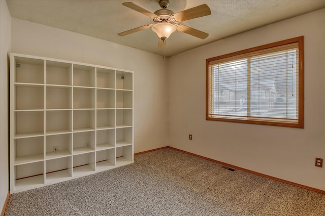 carpeted spare room with ceiling fan and a textured ceiling