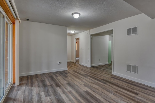 spare room with dark hardwood / wood-style floors and a textured ceiling