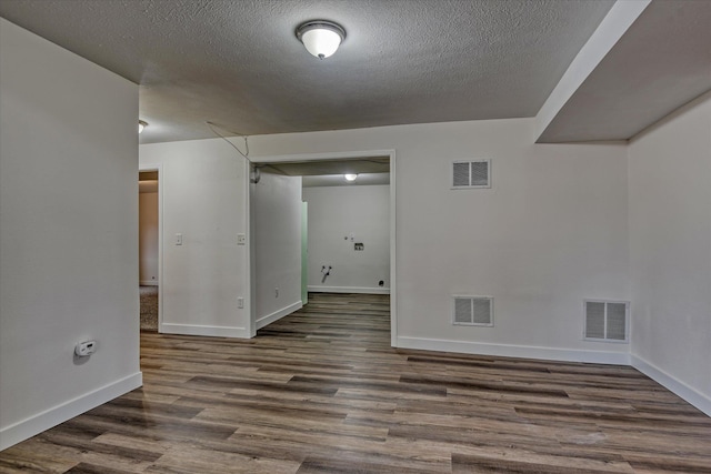 spare room featuring a textured ceiling and dark hardwood / wood-style floors