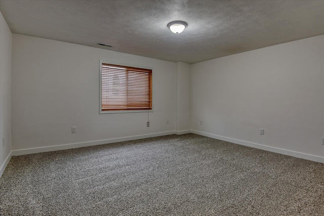 empty room with carpet floors and a textured ceiling