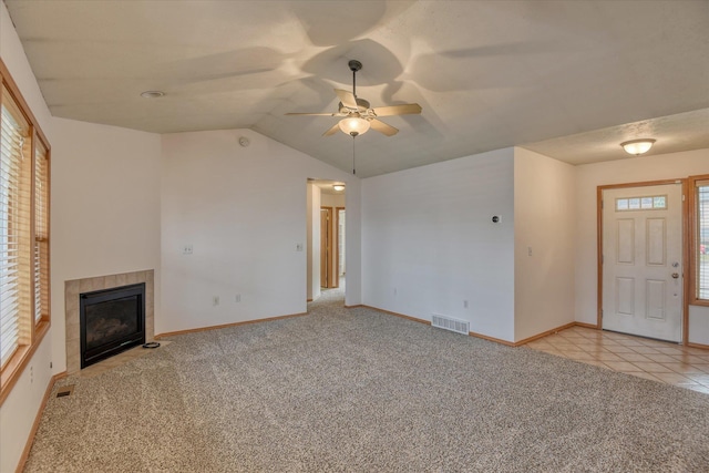 unfurnished living room featuring ceiling fan, light colored carpet, lofted ceiling, and a tile fireplace