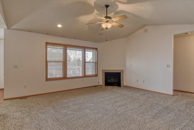 unfurnished living room with a tiled fireplace, ceiling fan, light colored carpet, and lofted ceiling