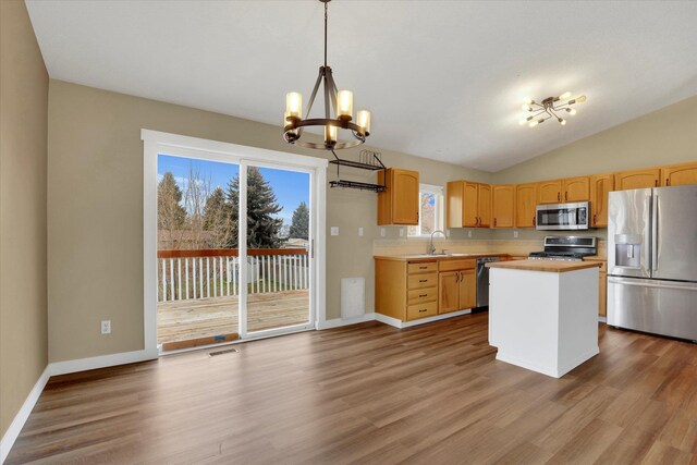 kitchen featuring hanging light fixtures, stainless steel appliances, an inviting chandelier, a kitchen island, and hardwood / wood-style flooring