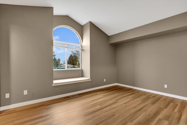 empty room with light hardwood / wood-style flooring and vaulted ceiling