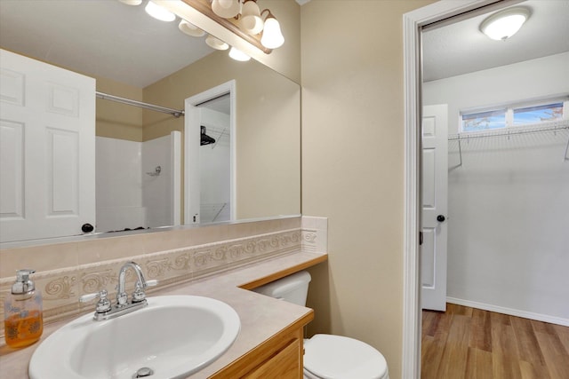 bathroom featuring tasteful backsplash, vanity, a shower, wood-type flooring, and toilet