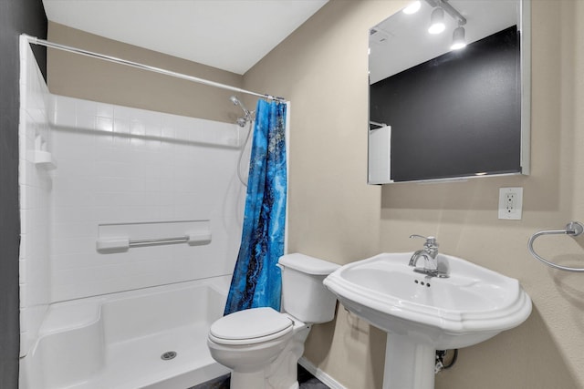 bathroom featuring toilet, curtained shower, and sink