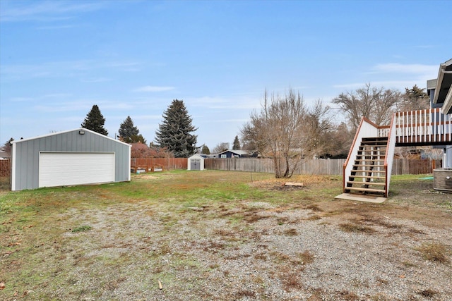 view of yard featuring a garage, a storage unit, and a deck