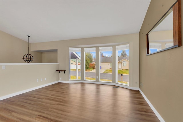 spare room with a chandelier and wood-type flooring