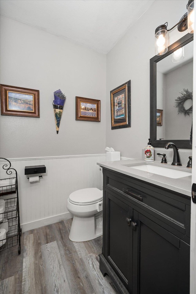 bathroom with hardwood / wood-style floors, vanity, and toilet