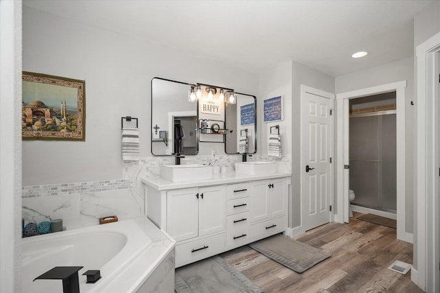 bathroom featuring a tub to relax in, vanity, wood-type flooring, and toilet