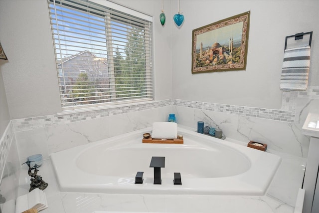 bathroom with tiled tub and a healthy amount of sunlight