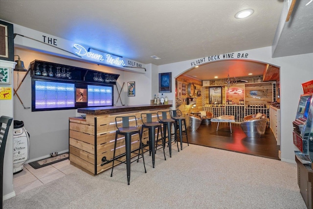 bar featuring light hardwood / wood-style floors and a textured ceiling