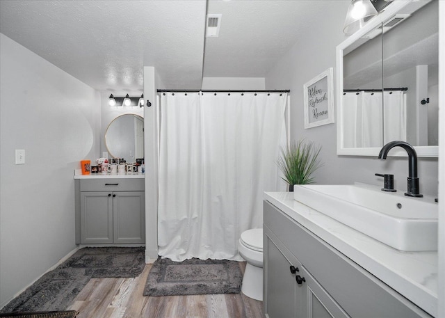 bathroom with toilet, vanity, a textured ceiling, and hardwood / wood-style flooring