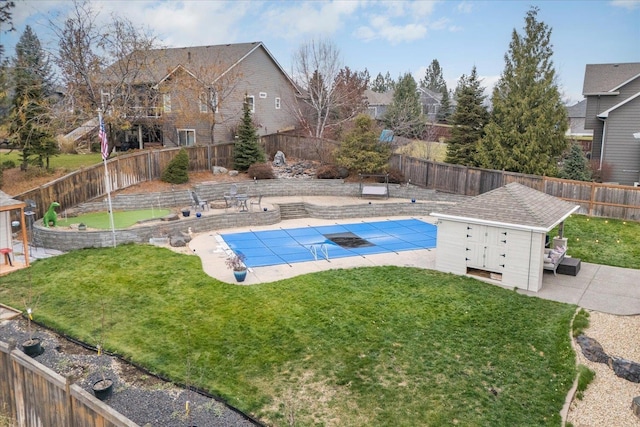 view of swimming pool featuring a yard, a shed, and a patio area