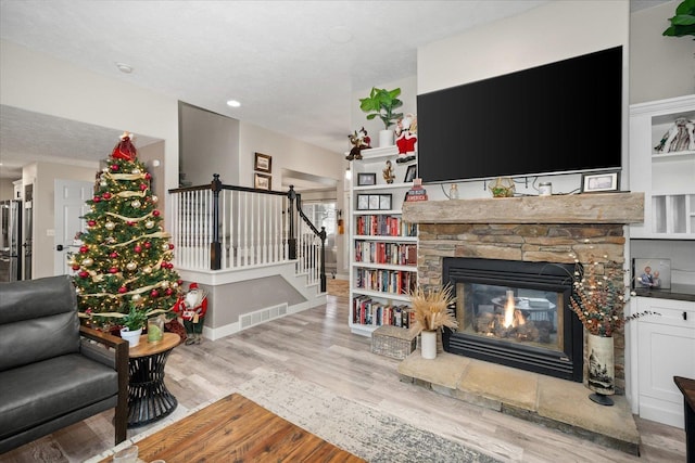 living room featuring a fireplace, a textured ceiling, and light wood-type flooring