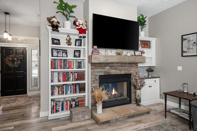 living room featuring hardwood / wood-style flooring, a stone fireplace, and a textured ceiling