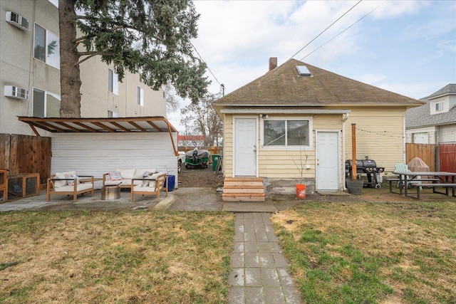 back of property with a wall mounted air conditioner, a patio, and a lawn