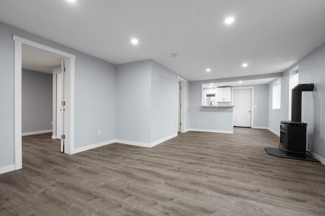 unfurnished living room featuring a wood stove and hardwood / wood-style floors