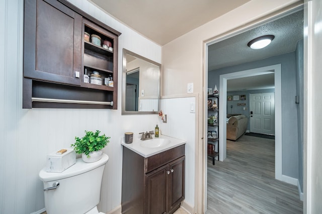 bathroom with vanity, toilet, wood-type flooring, and a textured ceiling