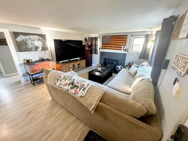 living room featuring a fireplace, a textured ceiling, and light wood-type flooring