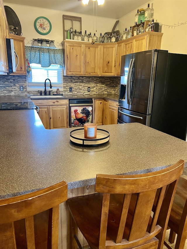 kitchen with a kitchen breakfast bar, sink, backsplash, and appliances with stainless steel finishes