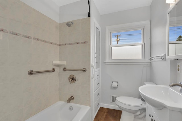 full bathroom featuring tiled shower / bath combo, toilet, wood-type flooring, and vanity