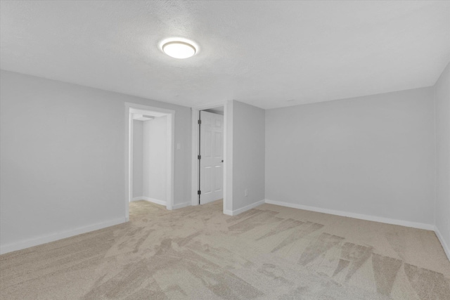 empty room featuring a textured ceiling and light colored carpet