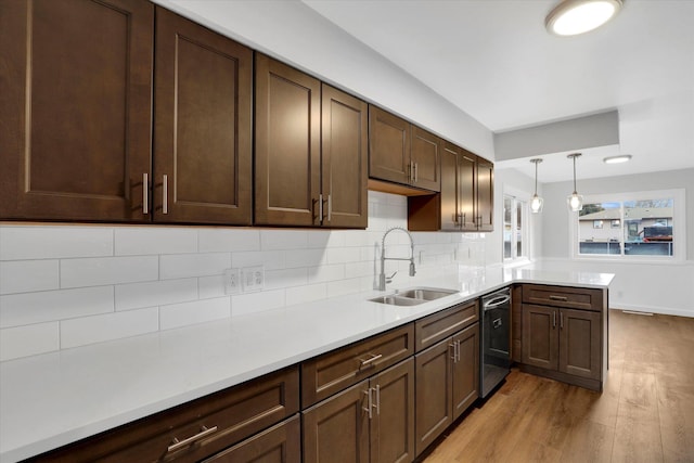 kitchen with sink, hanging light fixtures, stainless steel dishwasher, light hardwood / wood-style floors, and kitchen peninsula