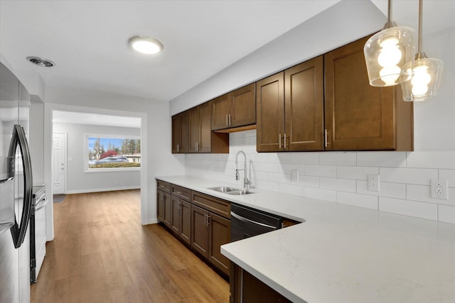 kitchen with decorative backsplash, appliances with stainless steel finishes, dark brown cabinetry, sink, and light hardwood / wood-style floors