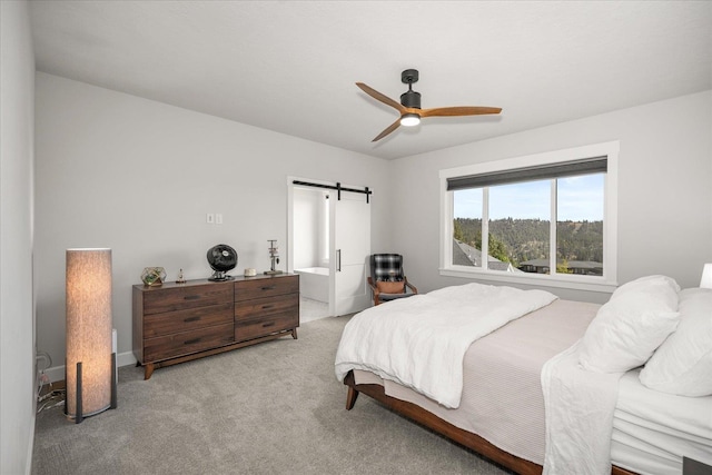 carpeted bedroom with a barn door and ceiling fan