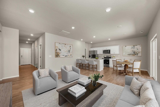 living room featuring a textured ceiling and light hardwood / wood-style floors