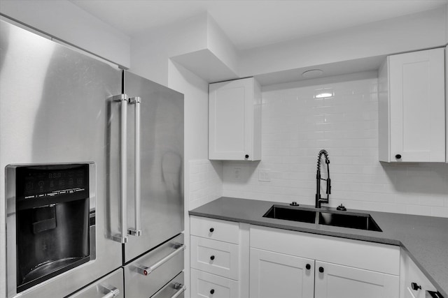 kitchen featuring decorative backsplash, white cabinetry, high end fridge, and sink