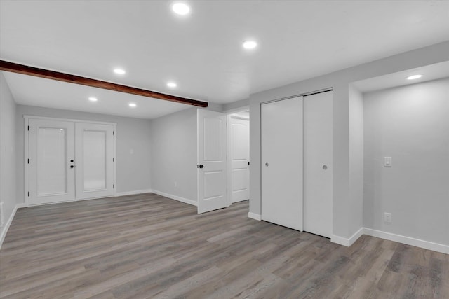 empty room featuring beamed ceiling and light wood-type flooring