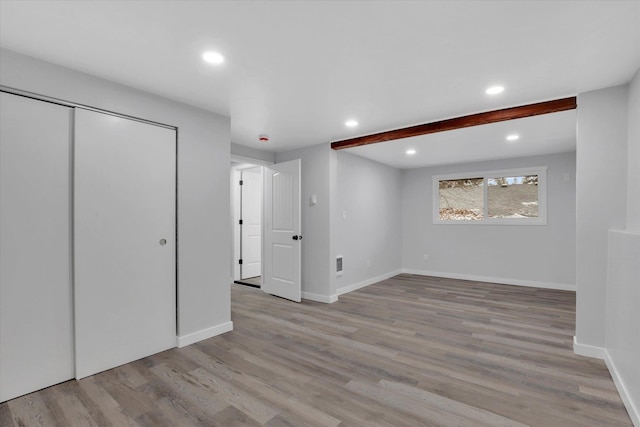 empty room featuring beamed ceiling and light wood-type flooring