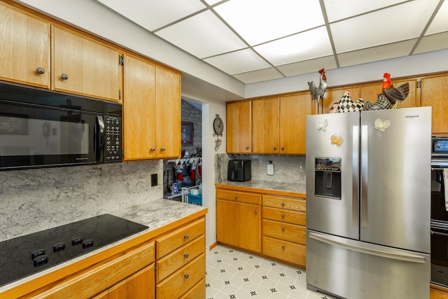 kitchen with a paneled ceiling, decorative backsplash, and black appliances