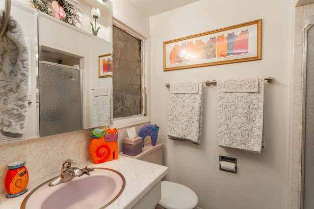 bathroom with decorative backsplash, vanity, toilet, and a shower with door