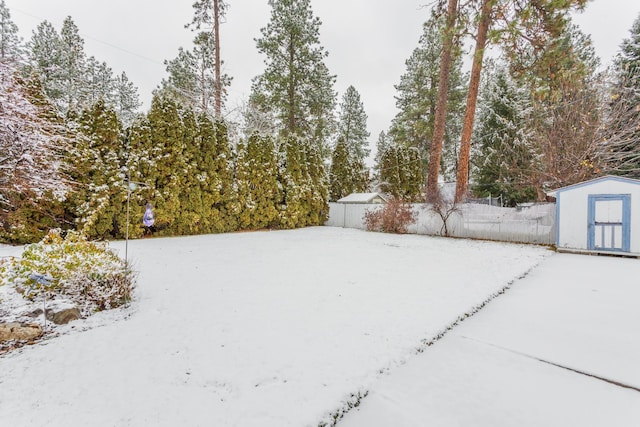 yard layered in snow with a storage shed