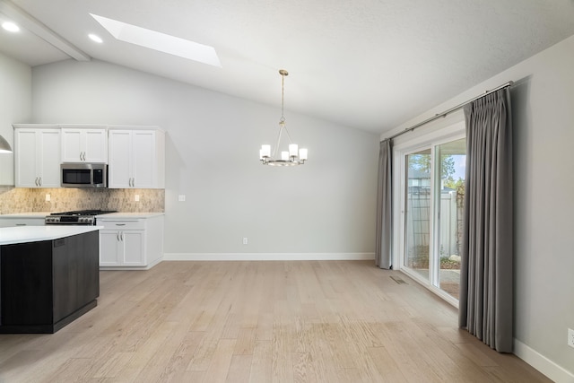 kitchen featuring lofted ceiling with skylight, white cabinets, stainless steel appliances, and light hardwood / wood-style floors