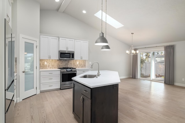 kitchen with a skylight, sink, stainless steel appliances, an island with sink, and white cabinets