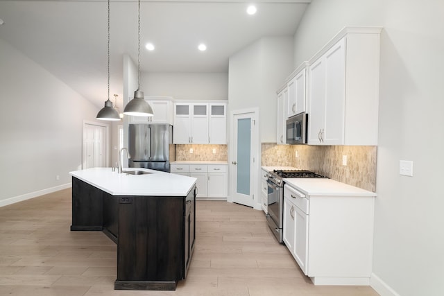 kitchen with appliances with stainless steel finishes, a kitchen island with sink, sink, pendant lighting, and white cabinets