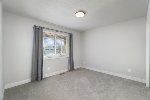 carpeted empty room featuring a textured ceiling