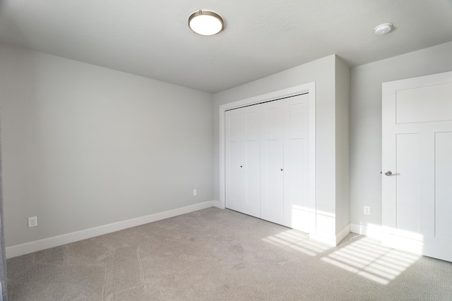 unfurnished bedroom with light carpet and a closet