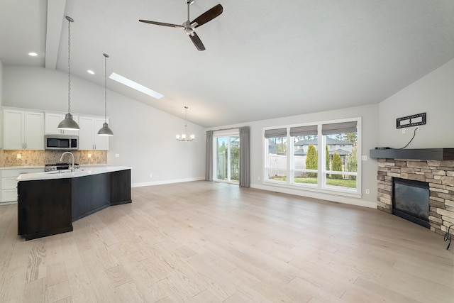 kitchen featuring white cabinets, hanging light fixtures, high vaulted ceiling, and light hardwood / wood-style flooring