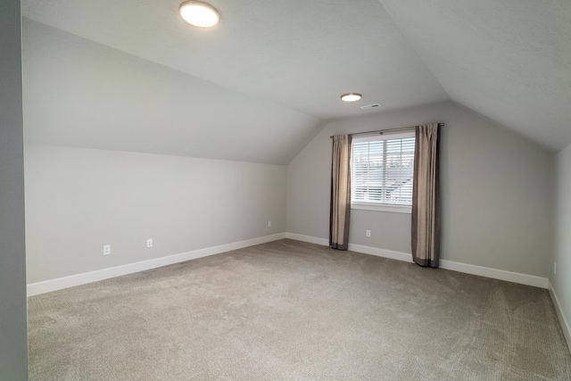 bonus room featuring light carpet and vaulted ceiling