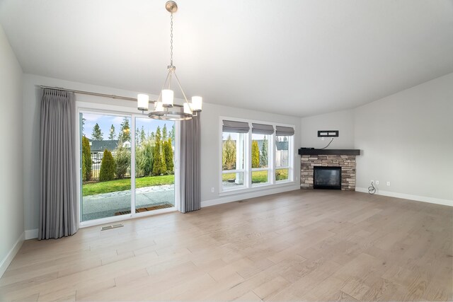 unfurnished living room with a fireplace, light hardwood / wood-style floors, and an inviting chandelier