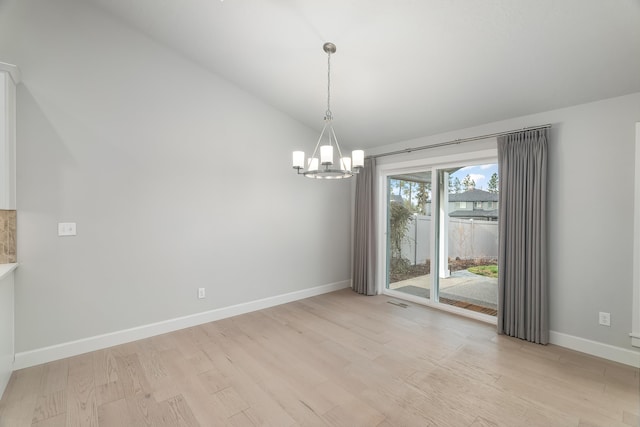 unfurnished dining area featuring a chandelier, light hardwood / wood-style floors, and vaulted ceiling