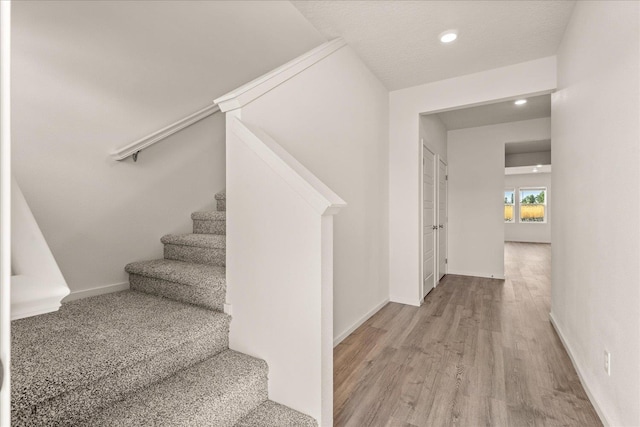 staircase with a textured ceiling and hardwood / wood-style flooring