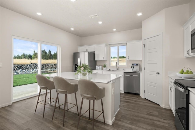 kitchen with appliances with stainless steel finishes, white cabinetry, a kitchen island, and sink