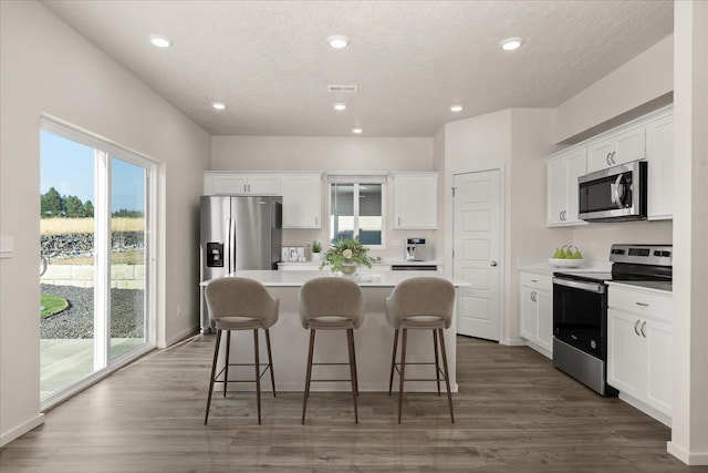 kitchen featuring white cabinets, dark hardwood / wood-style flooring, a center island, and stainless steel appliances